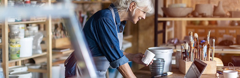 Female entrepreneur working in her pottery shop working on her business plan during Write a Business Plan Month in December.